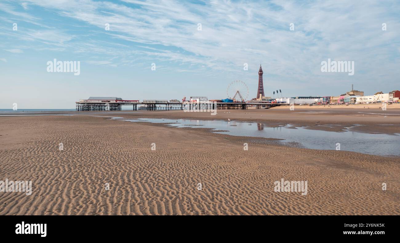 Ikonischer Pier und Turm heben sich von einer ruhigen Strandlandschaft ab, die die Ruhe der Ebbe widerspiegelt. Stockfoto