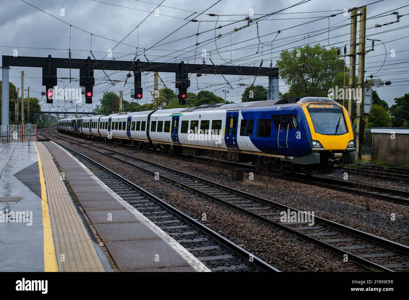 Moderner Elektrozug, der unter stürmischem Himmel auf Gleisen rasant fährt und den täglichen Transport vorstellt. Stockfoto