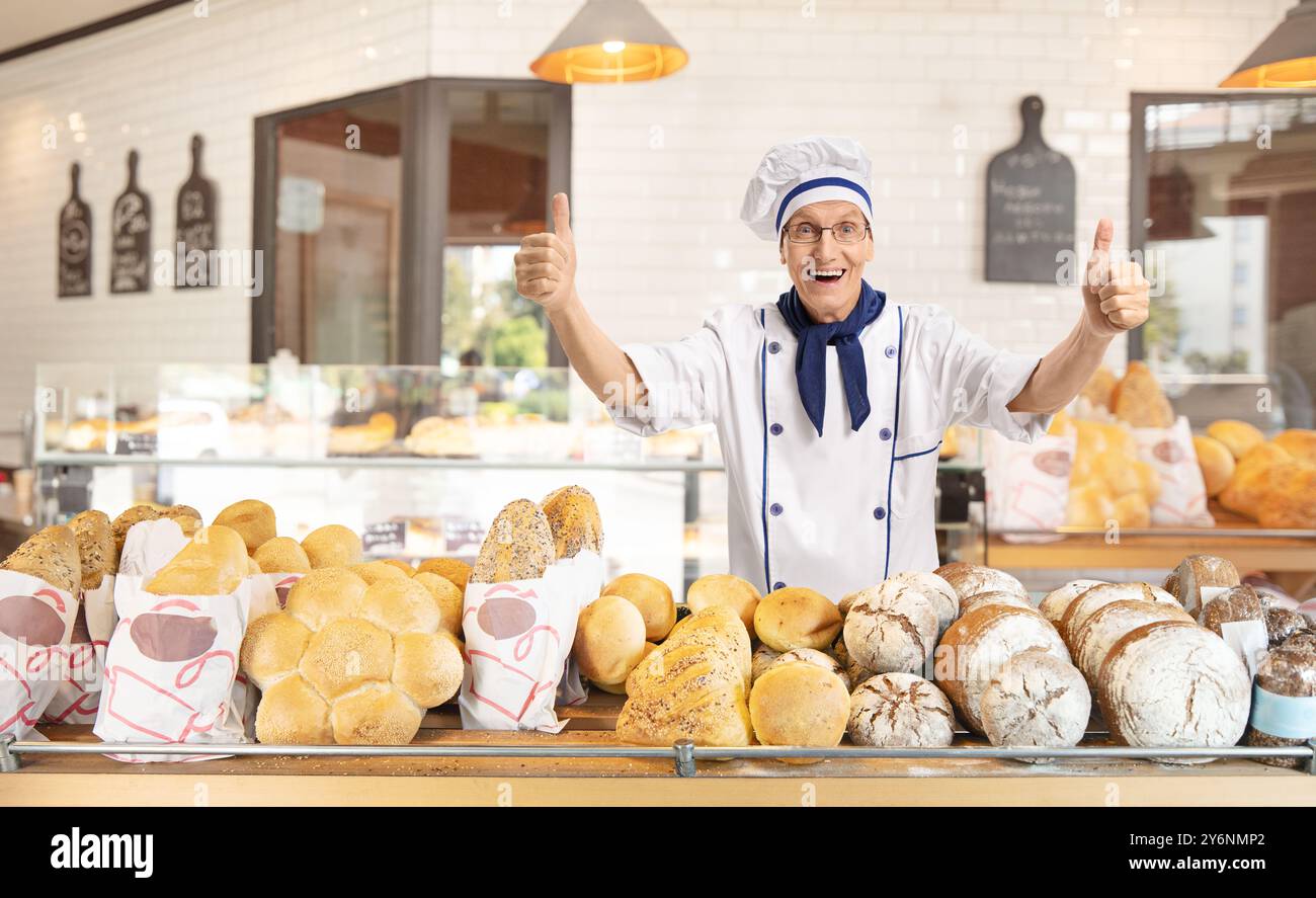 Überglückter Bäcker, der die Daumen in einer Bäckerei nach oben zeigt Stockfoto