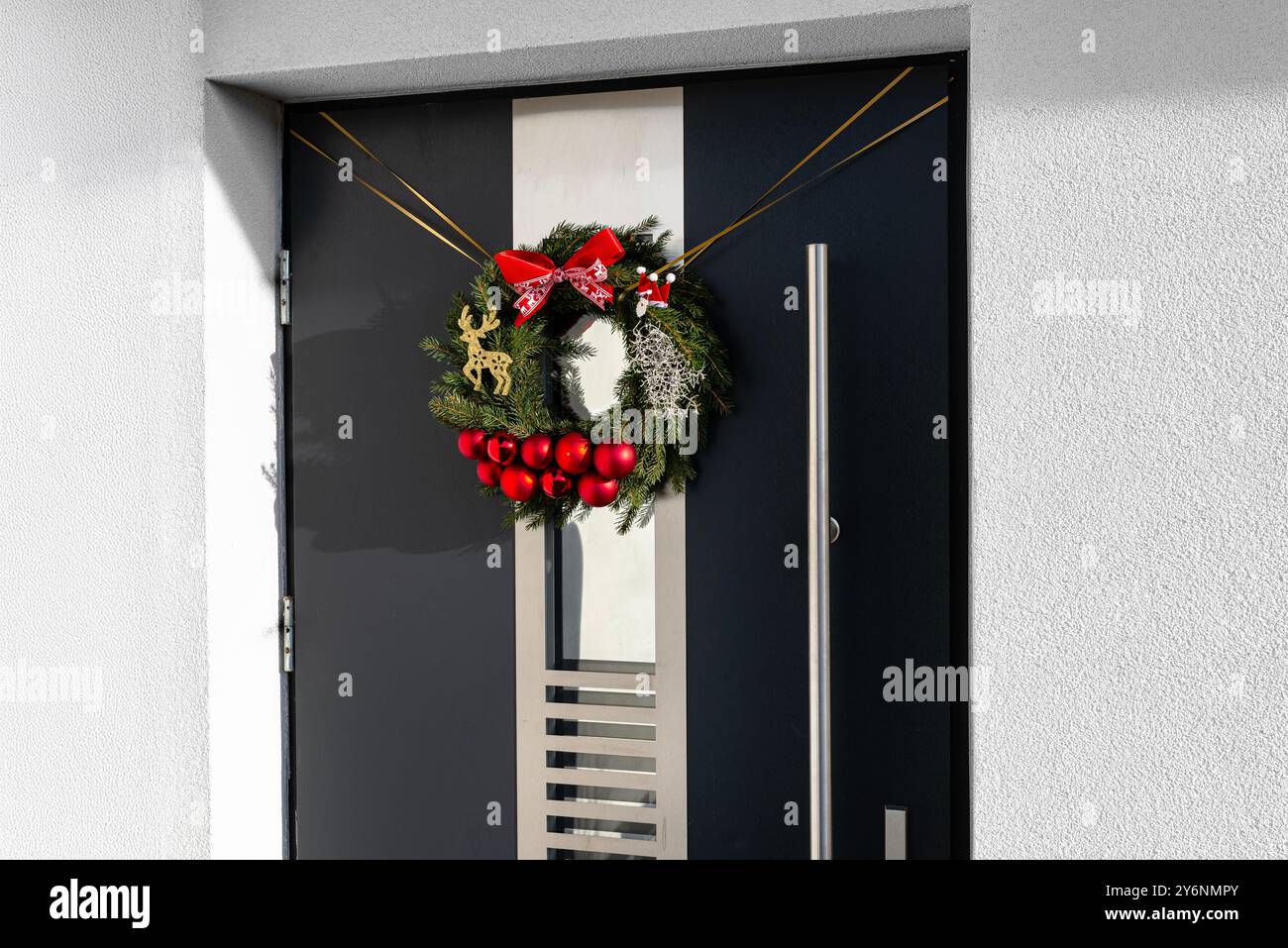 Weihnachtstürkranz aus Nadelzweigen, hängt an einer modernen Tür. Stockfoto