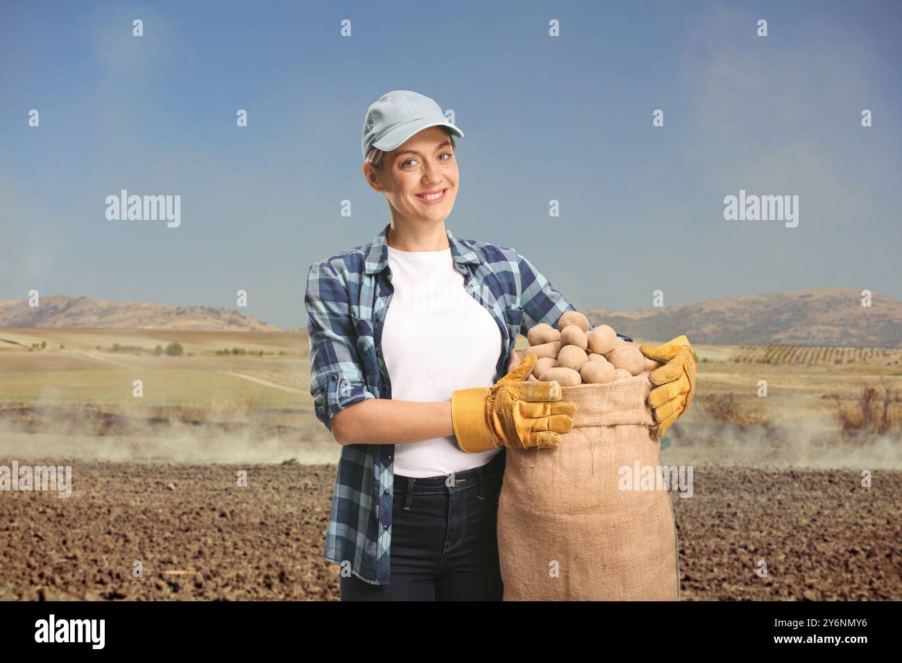 Junge Landwirtin, die Kartoffeln in einem Sack auf einem Feld hält Stockfoto