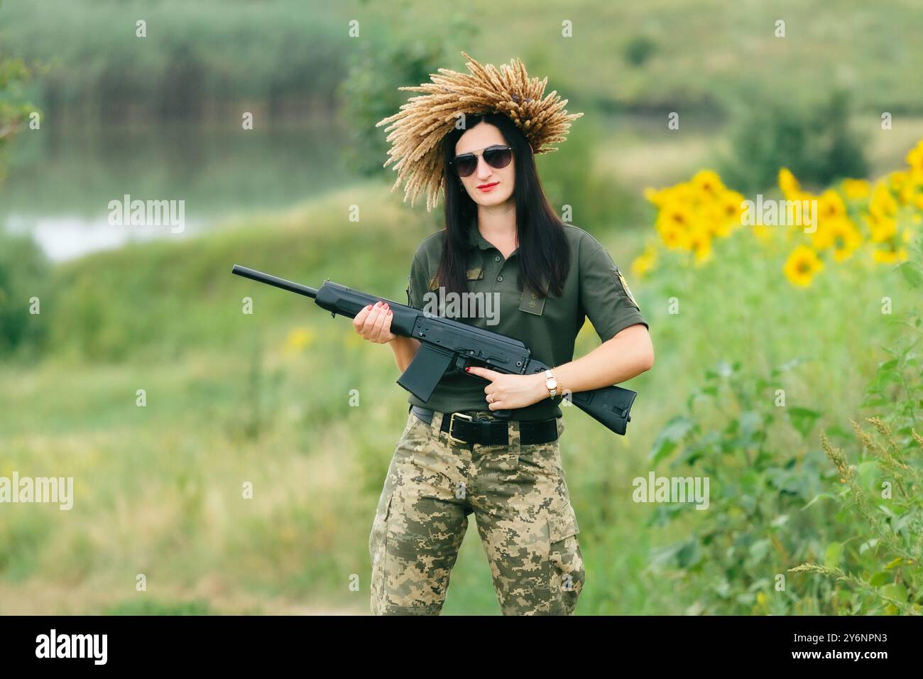 Soldatinnen in Militäruniform. Ein Mädchen in Militäruniform mit einer Waffe. Ukrainische Frau in einem Kranz. Stockfoto