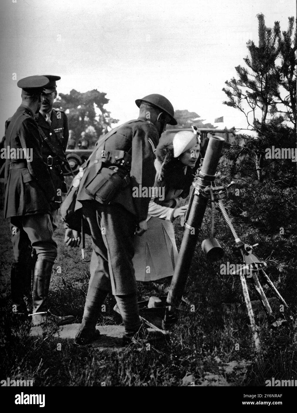Die Königin blickt durch die Sichtweite eines der 3-Zoll-Mörser, mit denen die Infanterie nun bewaffnet ist: Ihre Majestät mit einer Einheit des Aldershot Command April 1938 Stockfoto