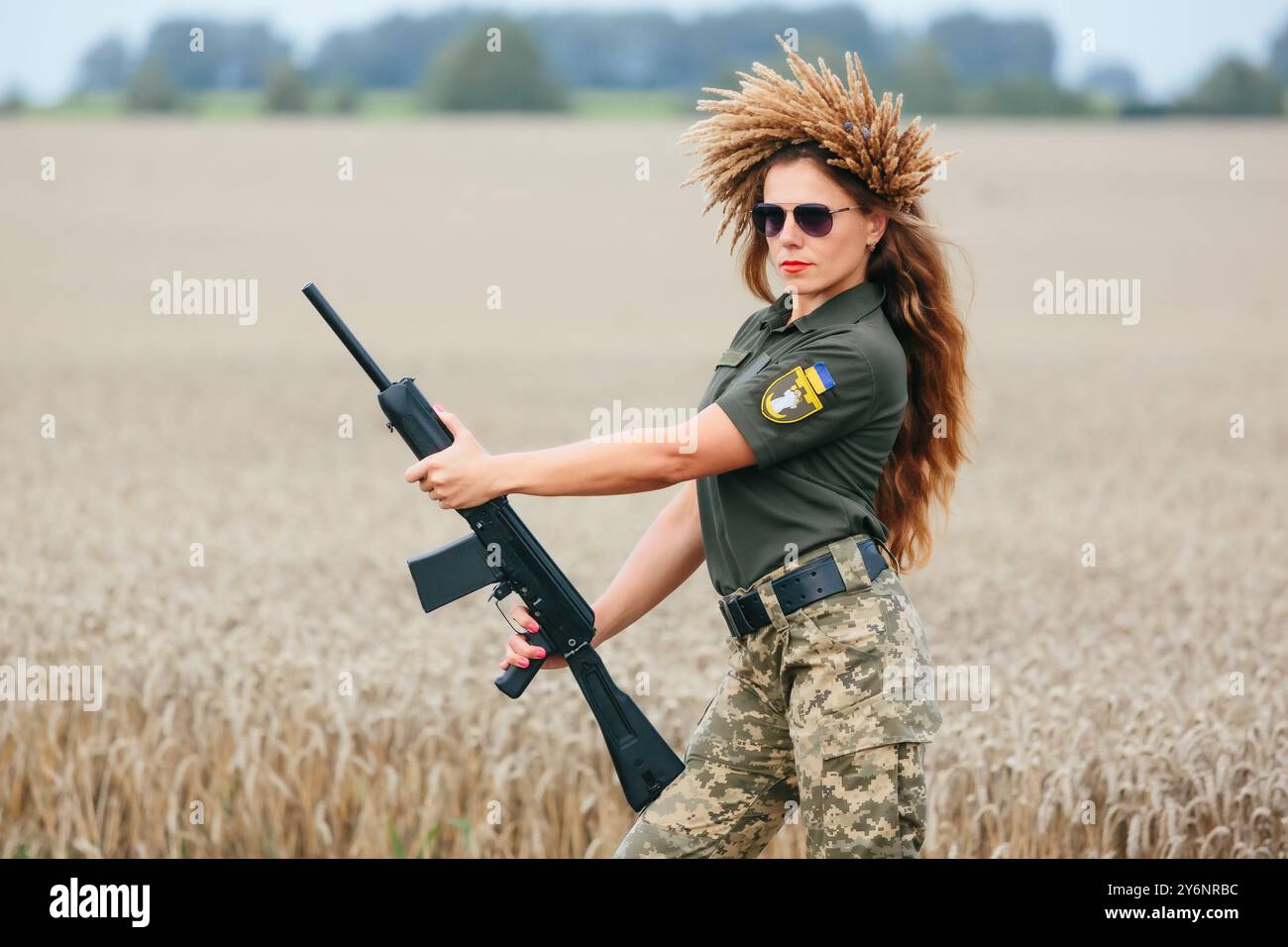 Soldatinnen in Militäruniform. Ein Mädchen in Militäruniform mit einer Waffe. Ukrainische Frau in einem Kranz. Stockfoto