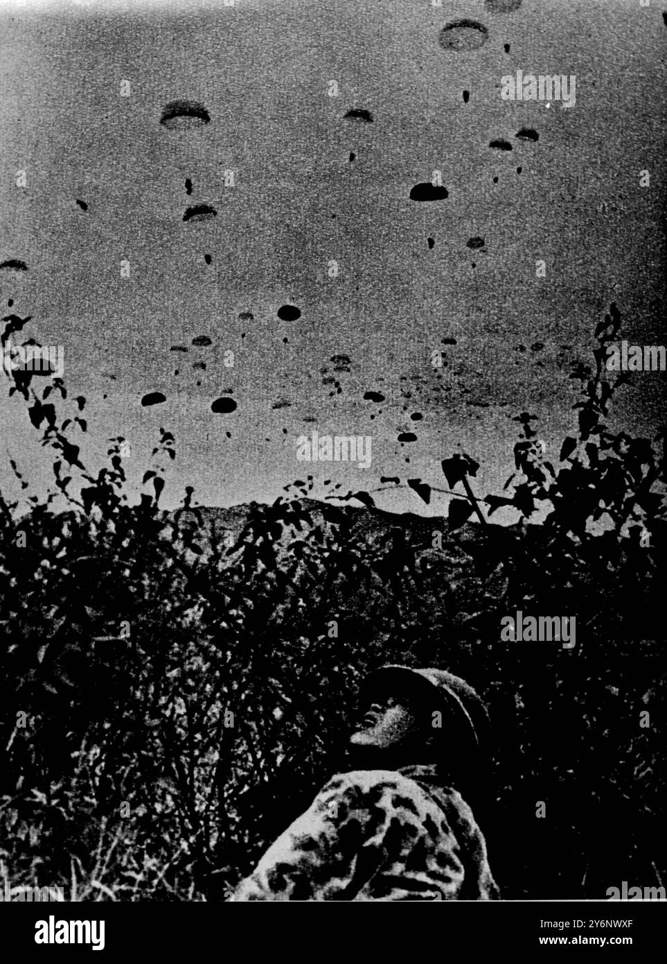 Ein Vietnamese, der von den Franzosen gezwungen wurde, sich der Armee anzuschließen, beobachtet amerikanische Flugzeuge, die Fallschirmjäger abwerfen. Die ursprüngliche Bildunterschrift wurde hinzugefügt... aber selbst sie konnten die Niederlage der Imperialisten nicht verhindern, während die Roten Dien Bien Phu sehen Stockfoto