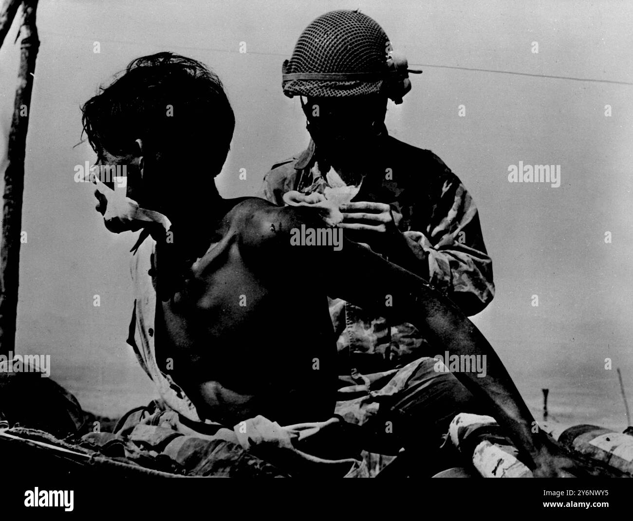 Noch immer tobt der Kampf um die französische Festung Dien Bien Phu in Nordindochina weiter. Und trotzdem werden die tapferen Verteidiger unter dem Kommando von General de Castries angesichts überwältigender Chancen zurückgetrieben. Sie stehen jetzt einem anderen Feind gegenüber, Matsch. Die Regenzeit hat begonnen. Ein französischer Soldat kümmert sich um die leichte Schulterwunde, die sein junger vietnamesischer Kamerad in Waffen trägt. Stockfoto