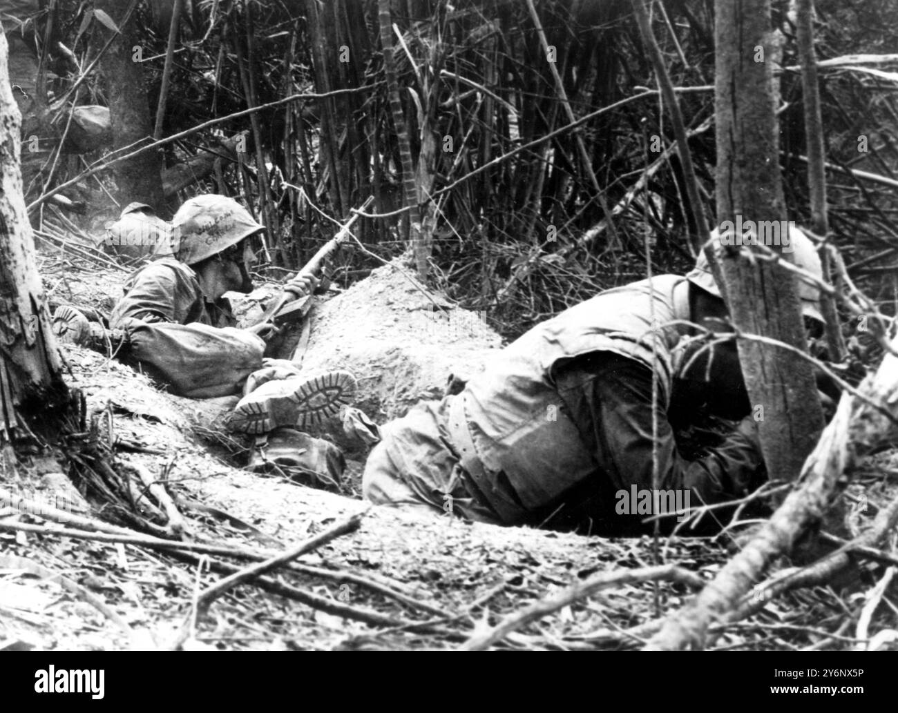 Dong Ha, Vietnam die US-Marines feuern in dichten Dschungel, während sie in hastig gegrabenen Fuchslöchern niedrig bleiben, während kommunistische Füchse während eines Kampfes auf dem Gebiet am 28. September 1966 verwelkenden Mörser und automatisches Waffenfeuer in die Position der Lesathernecks gießen. Stockfoto
