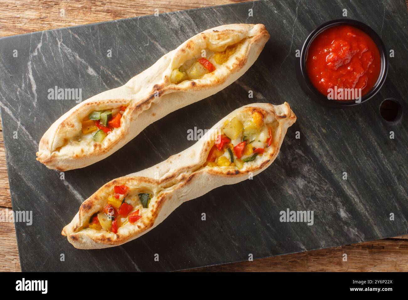 Portion Pizza sorrentine mit Käse und Gemüse Pfeffer, Tomaten, Artischocken, Zucchini Nahaufnahme auf einem Schieferbrett auf dem Tisch. Horizontale Draufsicht Stockfoto