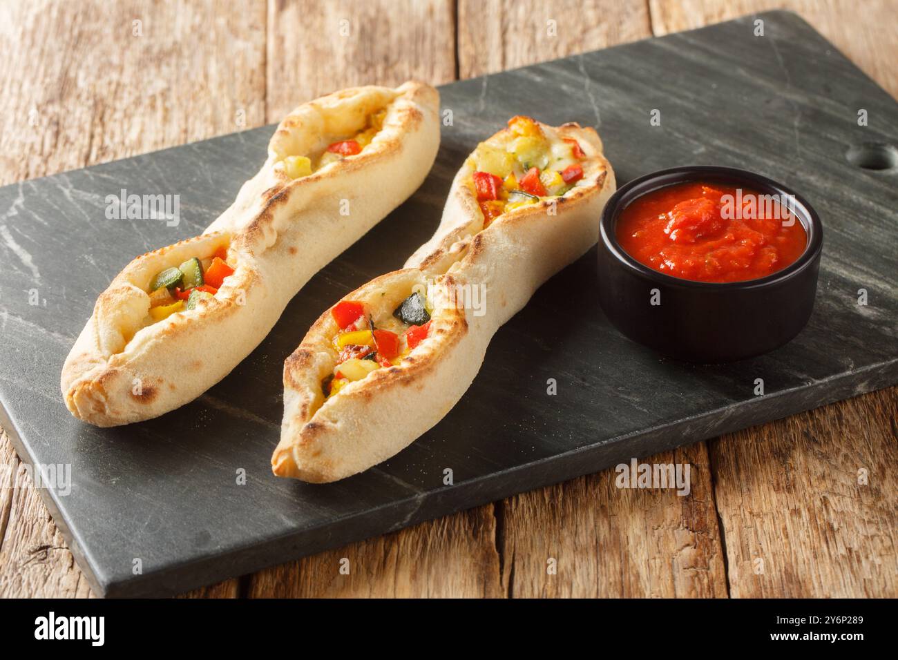 Vegetarische sorrentinische Pizza mit Mozzarella und Provolone Käse und Paprika, Tomaten, Artischocken, Zucchini, die im Holzofen gekocht werden Stockfoto