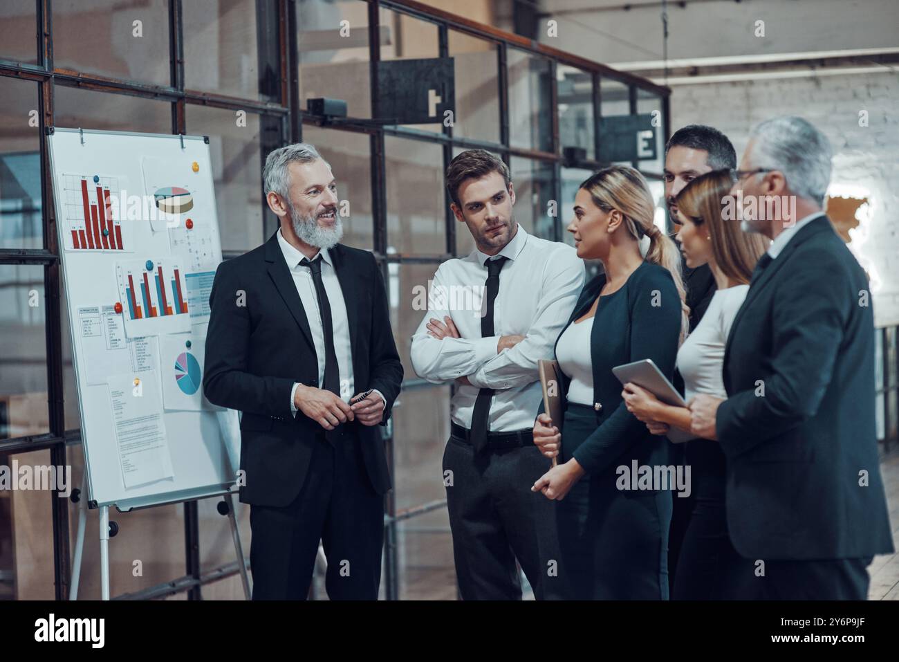 Professioneller Geschäftsexperte, der in Zusammenarbeit mit Kollegen in der Bürohalle Analyseberichte vorlegt Stockfoto