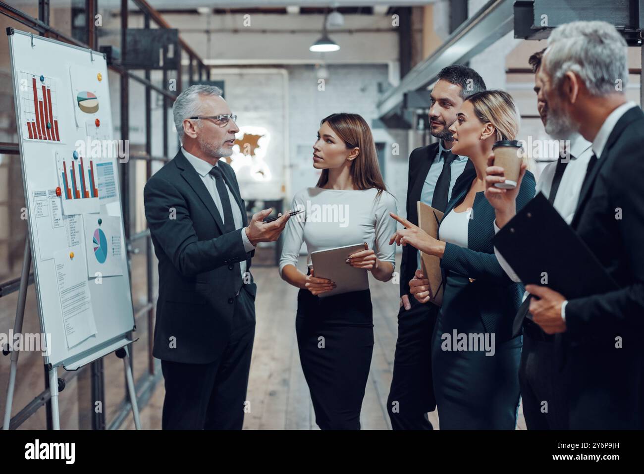 Professioneller Geschäftsexperte, der in Zusammenarbeit mit Kollegen in der Bürohalle Analyseberichte vorlegt Stockfoto