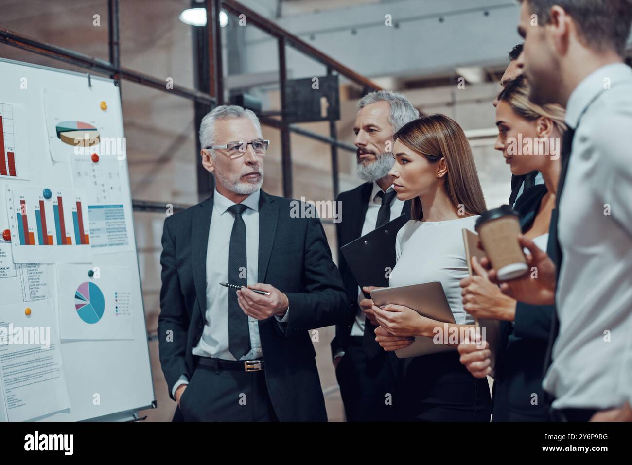 Professioneller Geschäftsexperte, der in Zusammenarbeit mit Kollegen in der Bürohalle Analyseberichte vorlegt Stockfoto
