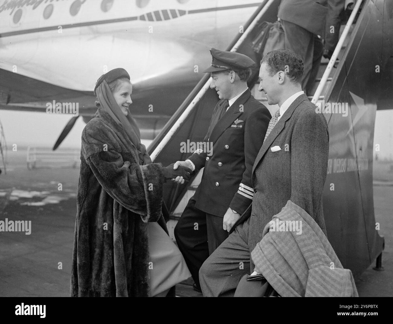 DIANA WYNARD FÜHRT SHAKESPEREANS AUF 14-WÖCHIGER AUSTRALIEN-TOUR DURCH. Mitglieder der Shakespearean Memorial Theatre Company in Stratford-upon-Avon, geleitet von Diana Wynyard und Anthony Quayle, dem Regisseur, verließen den Flughafen London mit B.O.A.C. Qantas Aircraft für eine vierzehnwöchige Tour durch Australien und Neuseeland. Die Firma gilt als die größte Theaterfirma, die jemals mit dem Flugzeug gereist ist. DAS BILD ZEIGT:- Diana Wynyard, die Schauspielerin, begrüßt den Piloten des Flugzeugs, Kapitän R. Uren, am Londoner Flughafen. Rechts ist Mr.. Anthony Quayle, der Regisseur. Oktober 1949 Stockfoto