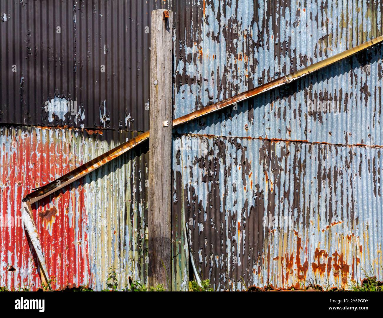 Detail einer gewellten Eisenwand auf einem Metallgebäude mit Anzeichen von Rost und Verfall. Stockfoto