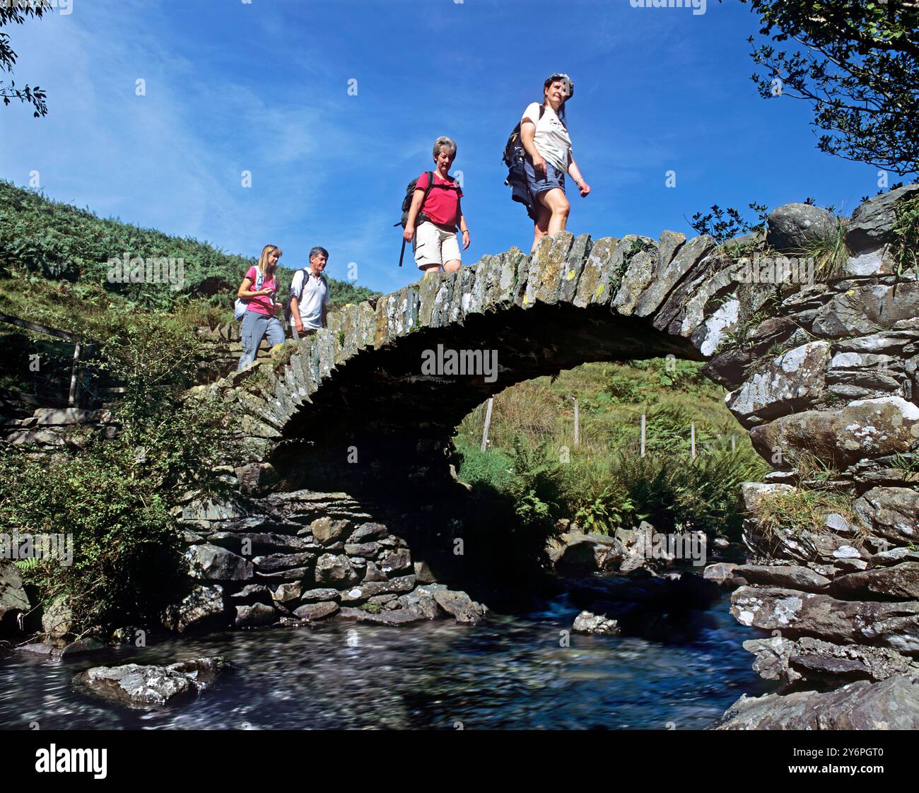 Wanderer überqueren die High Sweden Bridge über Scandale Beck in der Nähe von Ambleside im Lake District. Stockfoto