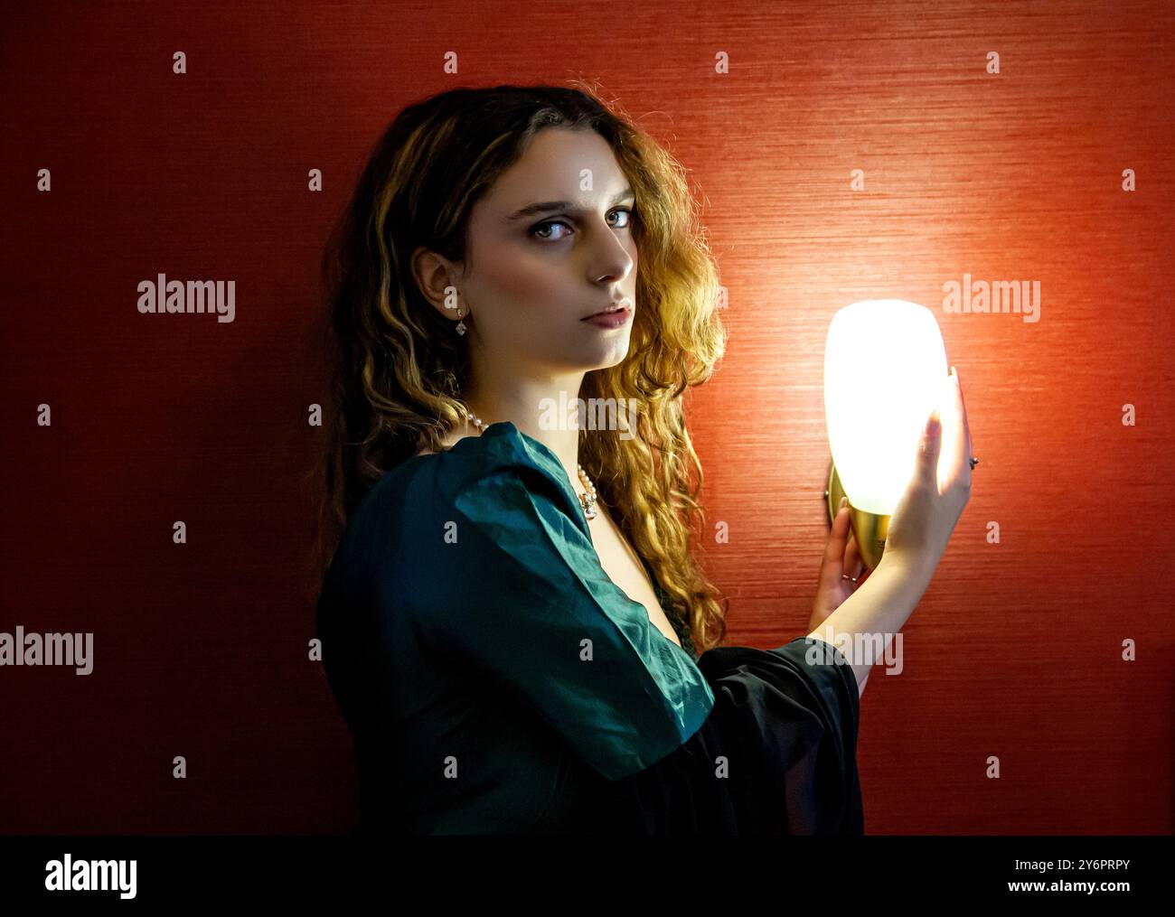 Ein hübsches weibliches Model sitzt neben einer hellen Nachttischlampe in einem Schlafzimmer im Dundee Queens Hotel und posiert für Fotos in Schottland Stockfoto Ein hübsches weibliches Model sitzt neben einer hellen Nachttischlampe in einem Schlafzimmer im Dundee Queens Hotel und posiert für Fotos in Schottland Stockfoto
