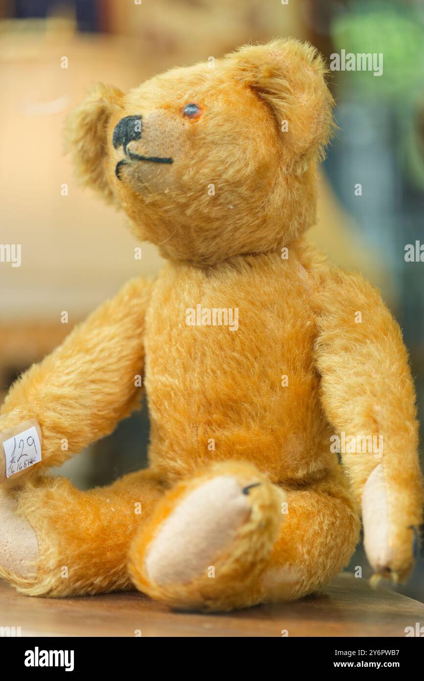 Ein altmodischer Kinderteddybär zum Verkauf, in einem Schaufenster. Sieht ziemlich skurril aus. Stockfoto