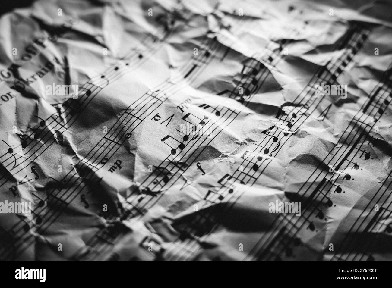 Eine Nahaufnahme zerknitterter Noten in Schwarz-weiß, die musikalische Noten und Textur hervorhebt. Stockfoto