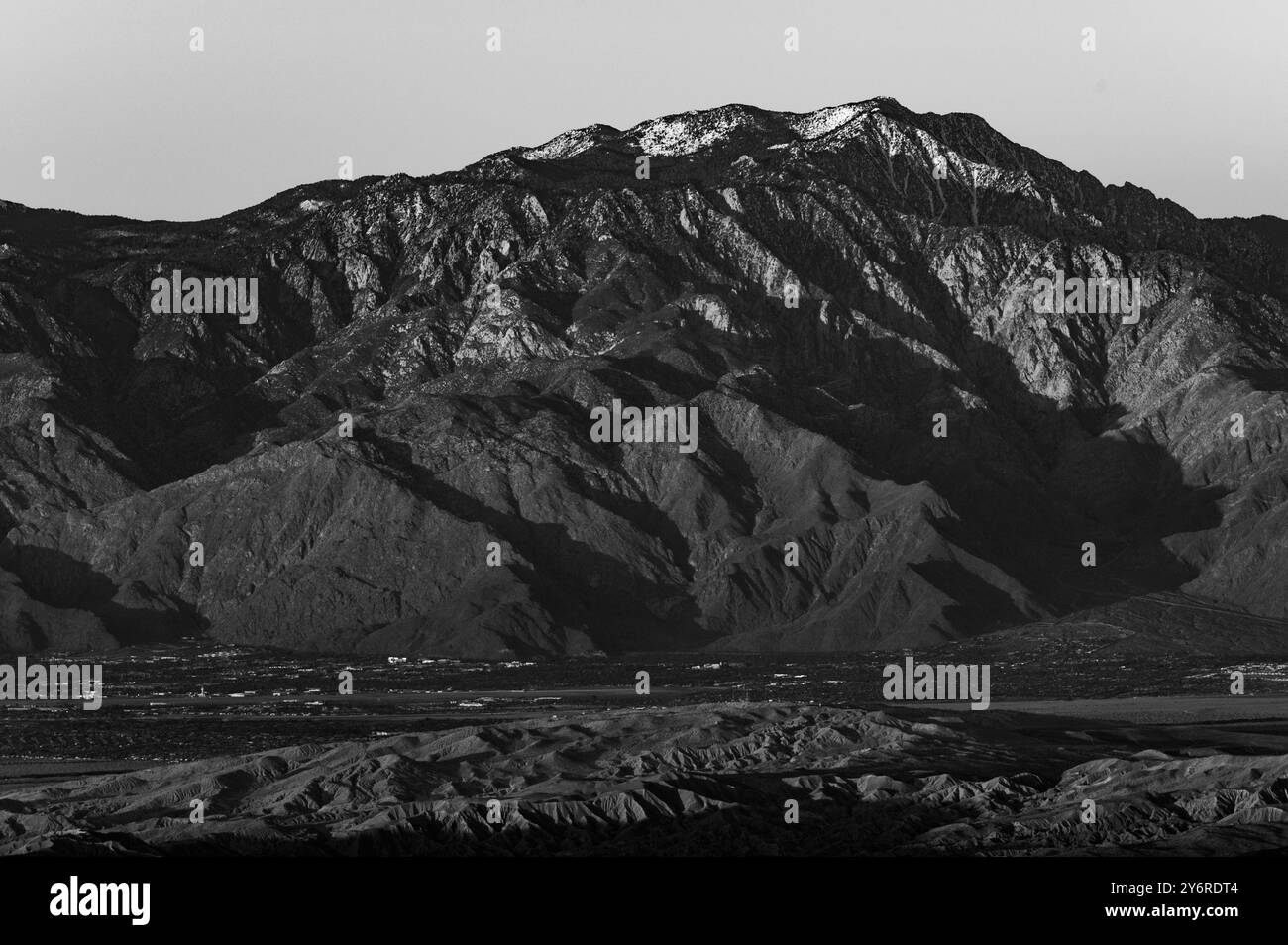 Schwarz-weiße Landschaft einer zerklüfteten Bergkette mit klarem Himmel im Hintergrund. Stockfoto