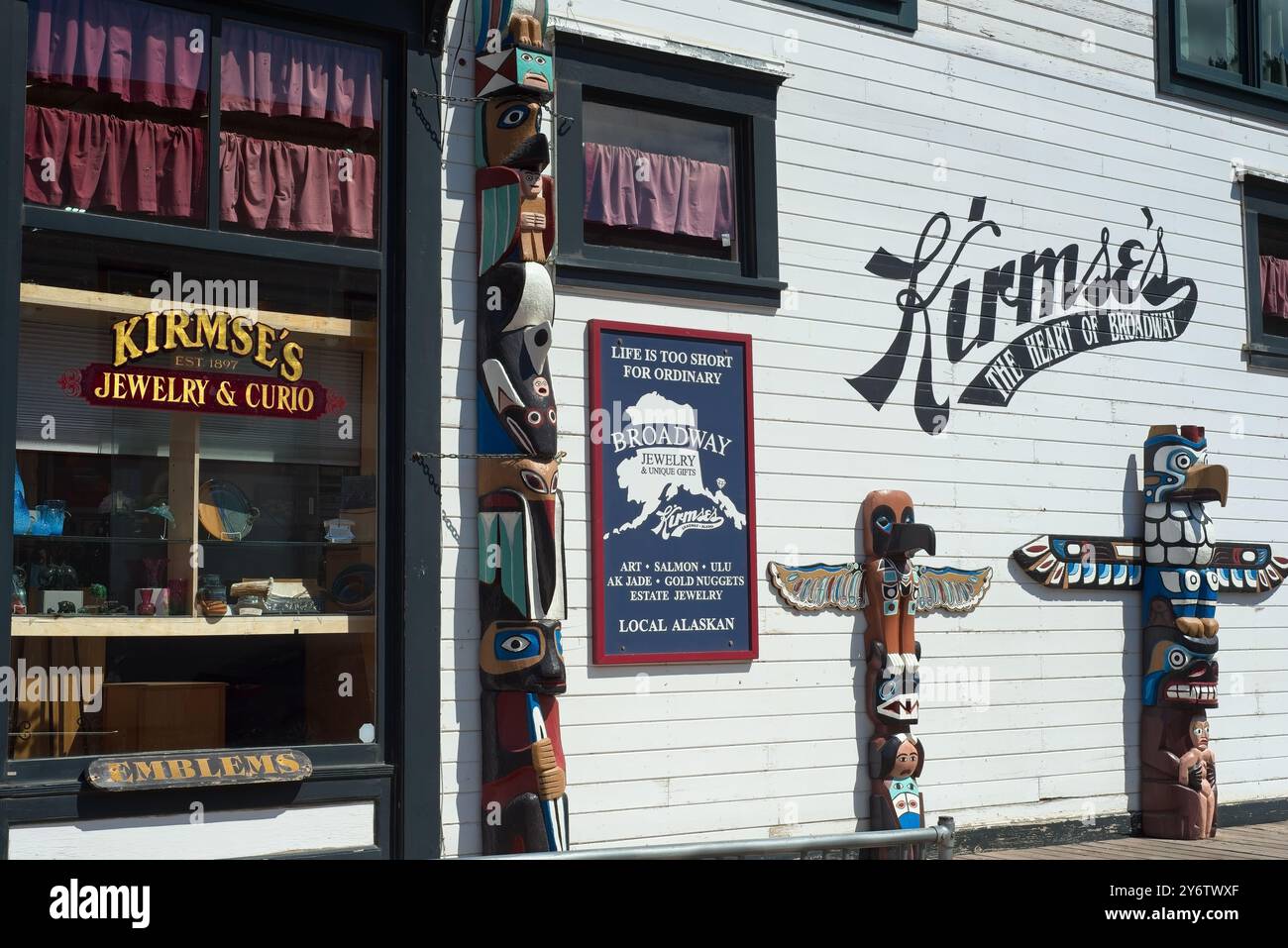 Skagway, AK, USA - 25. Juni 2024: Drei Totempfähle stehen draußen, um einen Schmuck- und Souvenirladen in Skagway zu besuchen. Stockfoto