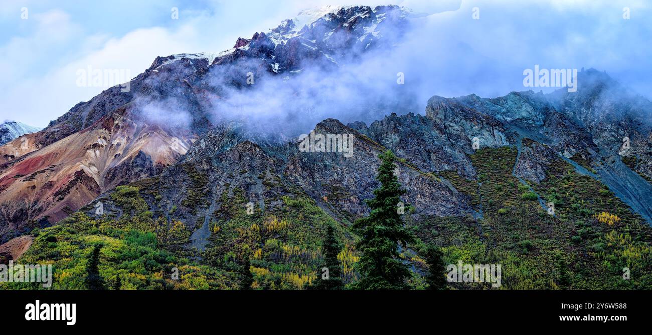 Zerklüftete Felsformationen und Herbstlaub zwischen den niedrigen hängenden Wolken auf den unteren Abschnitten des Sheep Mountain im südzentralen Alaska Stockfoto