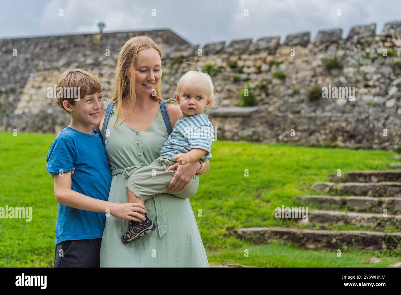 Mutter mit ihrem Kleinkind und ihren Söhnen im Teenageralter erforscht Fuerte de San Felipe de Bacalar. Familienreisen, kulturelles Erbe und historisches Abenteuerkonzept Stockfoto