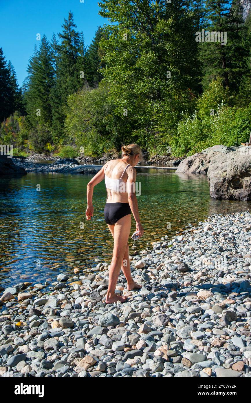 Seniorinnen laufen sanft über einen felsigen Strand entlang des Methow River in der Nähe von Mazama, Washington. USA Stockfoto