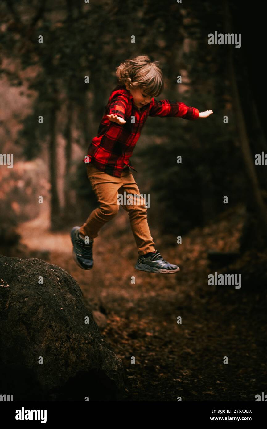 Kleines Kind, das in Herbstblättern im Wald spielt Stockfoto