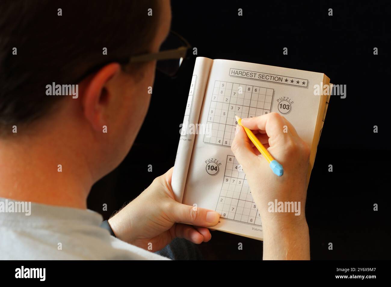 Über der Schulter Bild eines Mannes, der Sudoku-Puzzle macht Stockfoto