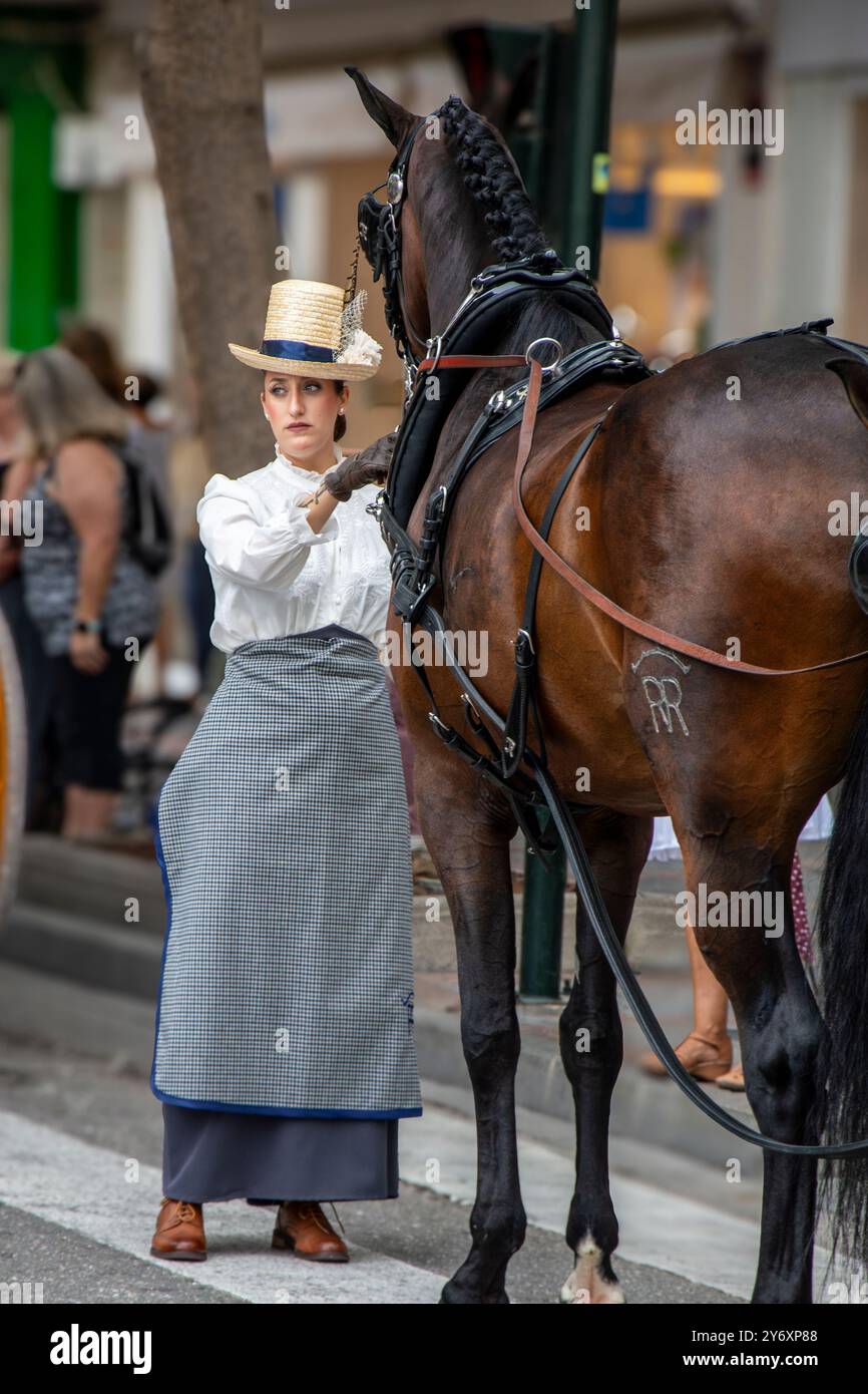 Eine Frau, die in historischen Kostümen und Hut mit ihrem Pferd auf den Straßen von Fuengirola während der Feier des Día del Caballo (Tag des Pferdes) gekleidet war. Stockfoto