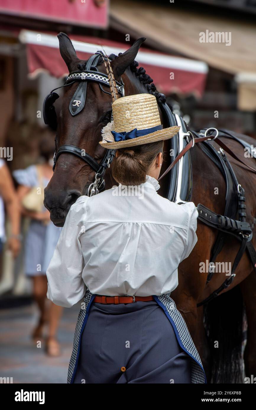 Eine Frau, die in historischen Kostümen und Hut mit ihrem Pferd auf den Straßen von Fuengirola während der Feier des Día del Caballo (Tag des Pferdes) gekleidet war. Stockfoto
