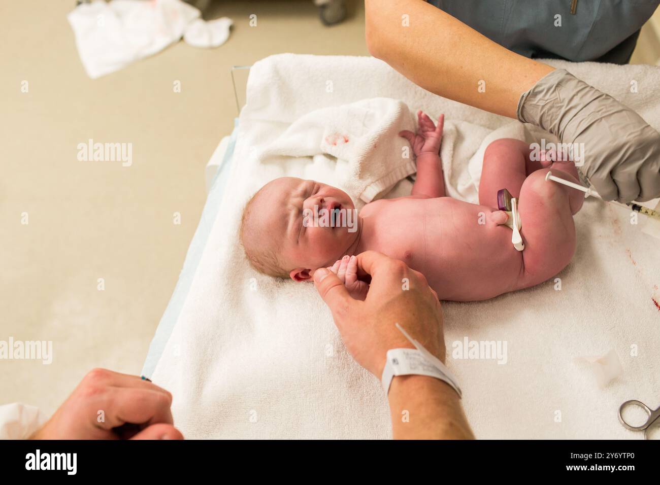 Das Neugeborene hält Dads Hand, während es Impfungen bekommt Stockfoto