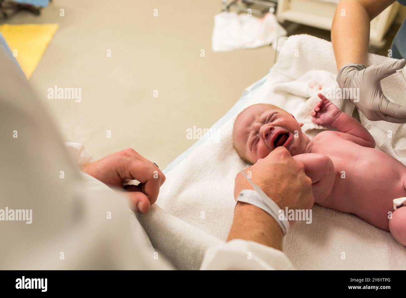 Baby weint auf dem Krankenhaustisch, während es Impfstoffe bekommt Stockfoto