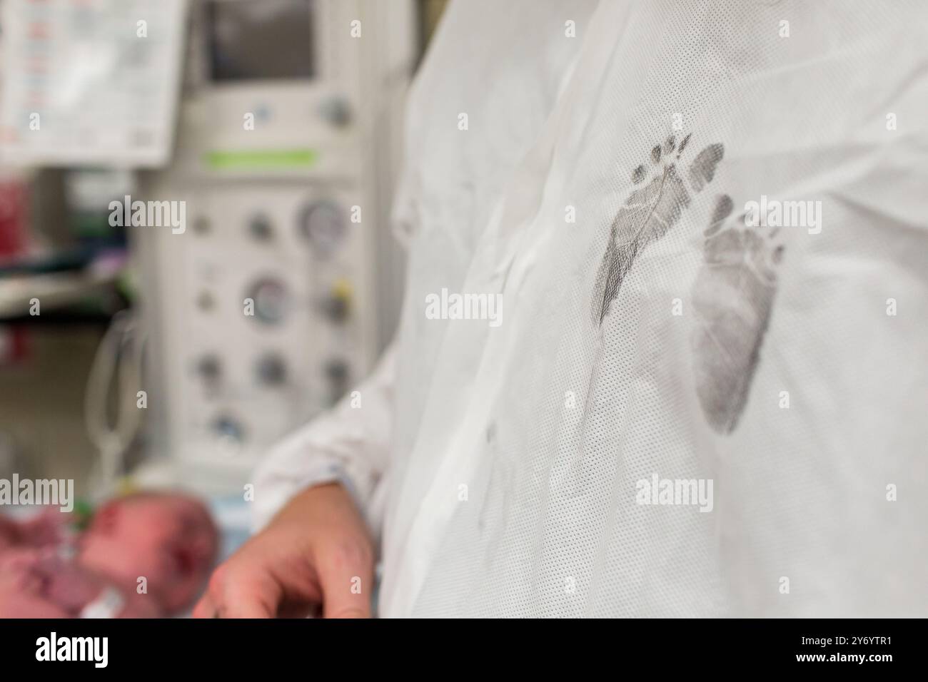 Neugeborene Babyfußabdrücke in Tinte auf Papas Krankenhauskleid Stockfoto