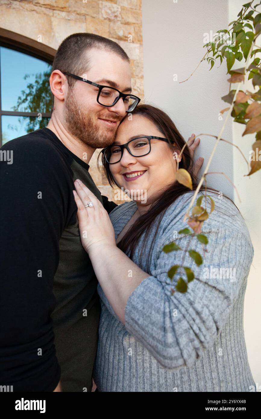 Ein lächelndes Paar, das sich eng umschließt und einen Verlobungsring zeigt Stockfoto