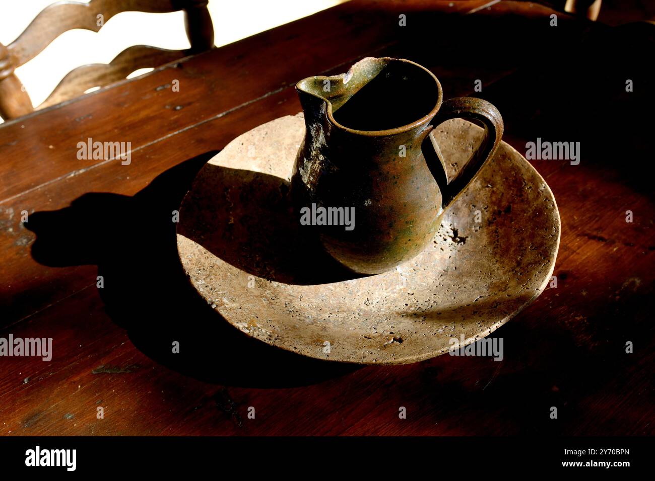 Handgemachte Kanne und Schüssel auf Holztisch mit Licht und Schatten Stockfoto