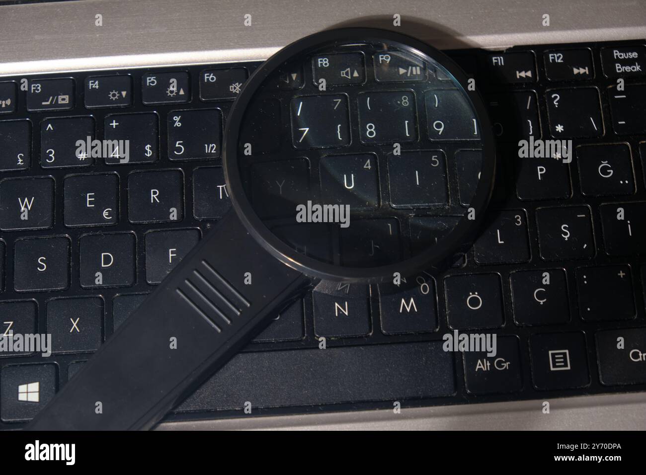 Modernes Vergrößerungsglas auf einer schwarzen Laptop-Tastatur in einer von der Technik inspirierten Nahaufnahme Stockfoto