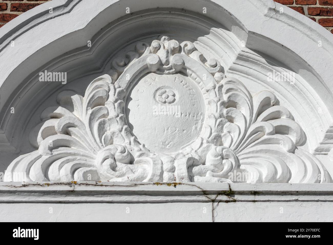 Klassisches weißes Portaltympanon mit Schild- und Federschmuck. Freimaurerkirche. Nexo, Dänemark Stockfoto