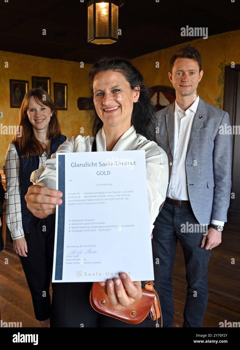 Seitenroda, Deutschland. September 2024. Irene Schmidt (l-r) von Saale-Unstrut Tourismus GmbH, Ulrike Kaiser von Schloss Leuchtenburg und Johann Waschnewski (CDU), Landrat des Landkreises Saal-Holzland, stehen auf Schloss Leuchtenburg nebeneinander. Zuvor erhielt die Leuchtenburg einen Tourismuspreis, den Saale-Unstrut Gold Highlight. Die Burg Leuchtenburg ist als „Königin des Saaletals“ bekannt. Sie wurde erstmals 1221 urkundlich erwähnt. Quelle: Martin Schutt/dpa/Alamy Live News Stockfoto