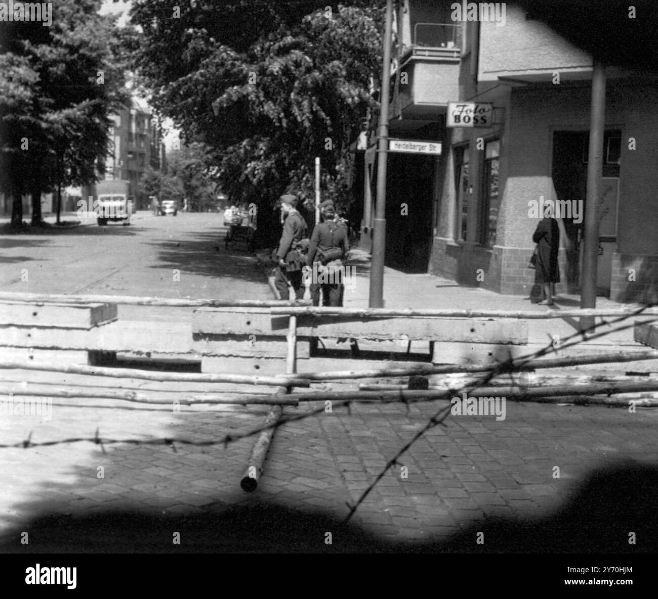 Der Tunnel , durch den am Pfingstwochenende fast zwanzig Ostberliner in West-Berlin entflohen , begann im Untergeschoss dieses Eckhauses ( rechter Hintergrund ) ein Fotoausrüstungsgeschäft . Das Bild wurde an der Grenze gemacht und die ostdeutsche Polizei wird draußen gezeigt . 13. Juni 1962 Stockfoto