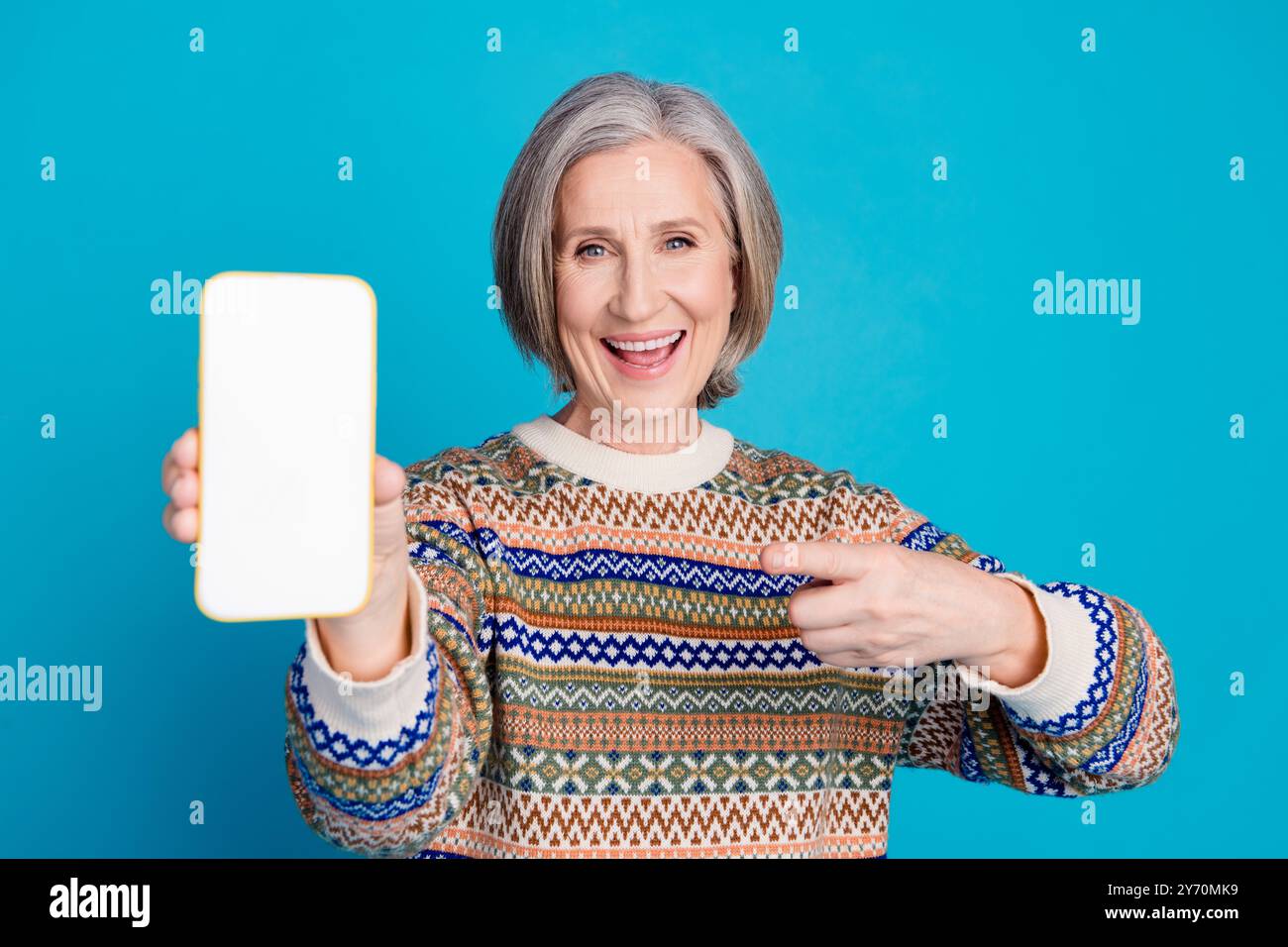 Foto der fröhlichen Frau tragen Ornament Pullover, der auf qr-Code auf dem Smartphone-Bildschirm anzeigt leerer Raum isoliert auf blauem Hintergrund Stockfoto