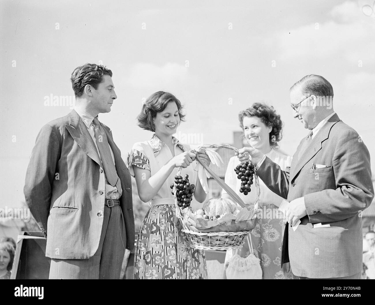 OBSTKORB FÜR MISS " ATOMENERGIE " MISS ATOMENERGIE " war der ungewöhnliche Titel , um den heute bei einem Schönheitswettbewerb gekämpft wurde . Es war eines der Veranstaltungen auf der jährlichen Sportversammlung der Mitarbeiter der Atomenergieforschungseinrichtung in Harewell ( Berks ) , und der Richter war DERRICK DE MARNEY , der Film - und Bühnenstar . DAS BILD ZEIGT: SIR JOHN COCKCROFT, Direktor des Atomforschungsinstituts Harwell, überreicht dem Gewinner des Titels "Miss Atomic Energy" einen Obstkorb. Von links nach rechts; DERRICK DE MARNEY, JEAN THEOBALD, aus Ardington (Berks), Sieger, Frau Molly Stockfoto