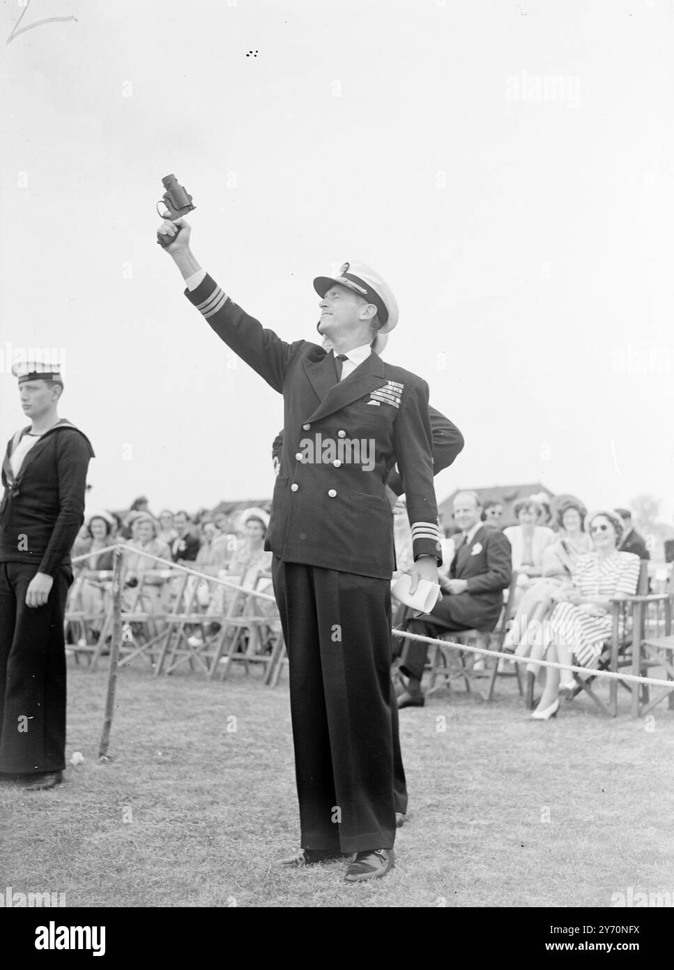 COMMANDER FAIRBANKS BEGINNT MIT DER FLOTTENAUSSTELLUNG in der Uniform eines Kommandanten der United States Navy, der Filmschauspieler Douglas Fairbanks feuert eine Pistole ab, um die Flugschau zu starten, als er an einem Naval Air Day auf der H.M.S. Hornbill, der Royal Navy Air Station in Culham bei Abingdon, Berks, teilnahm. Herr Fairbanks, der in Großbritannien ist, um einen Film zu drehen, verbrachte einen Teil seines Kriegsdienstes als Lieutenant Col in den Flugzeugträgern der US Navy. Er wurde mit dem British Distinguished Service Cross für seine Verdienste um die alliierte Sache ausgezeichnet und wurde seitdem zum Ehrenkommando der britischen EMPI ernannt Stockfoto