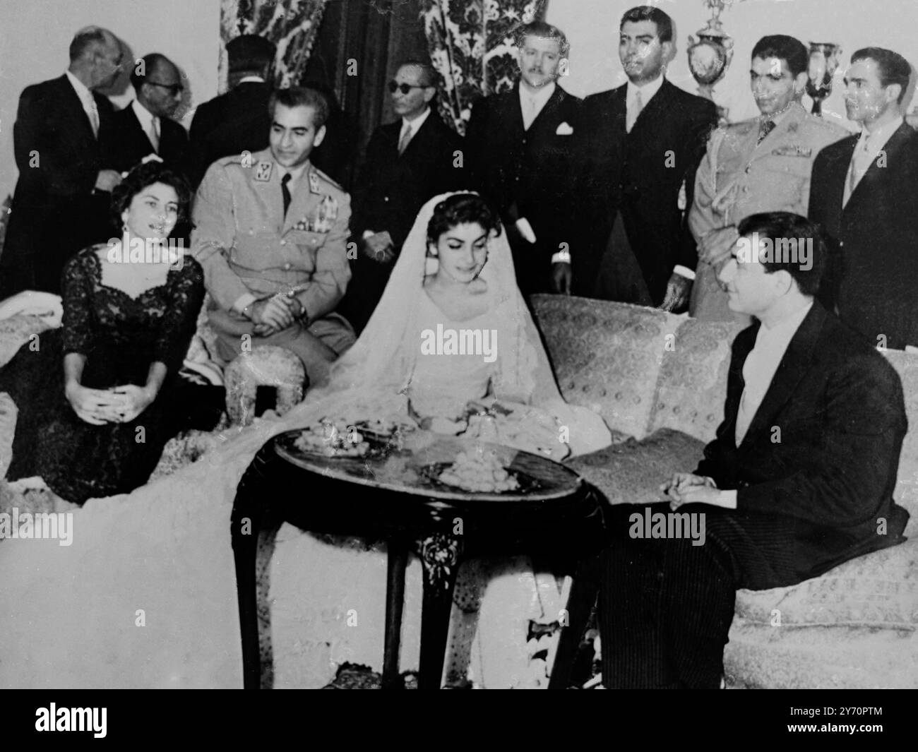 Prinzessin Shahnaz Pahlevi , 17-jährige Tochter des iranischen Schah Reza Pahlevi und seiner ersten Frau , saß mit ihrem Ehemann Ardeshi Zahedi , dem Sohn von General Fazollah Zahedi , einem ehemaligen iranischen Premierminister kurz nach der Hochzeitszeremonie . Auf der linken Seite sitzt Königin Soraya von Persien , auf dem Arm sitzt ihr Mann der Schah von Persien und dahinter sind Onkel . 12. Oktober 1957 Stockfoto