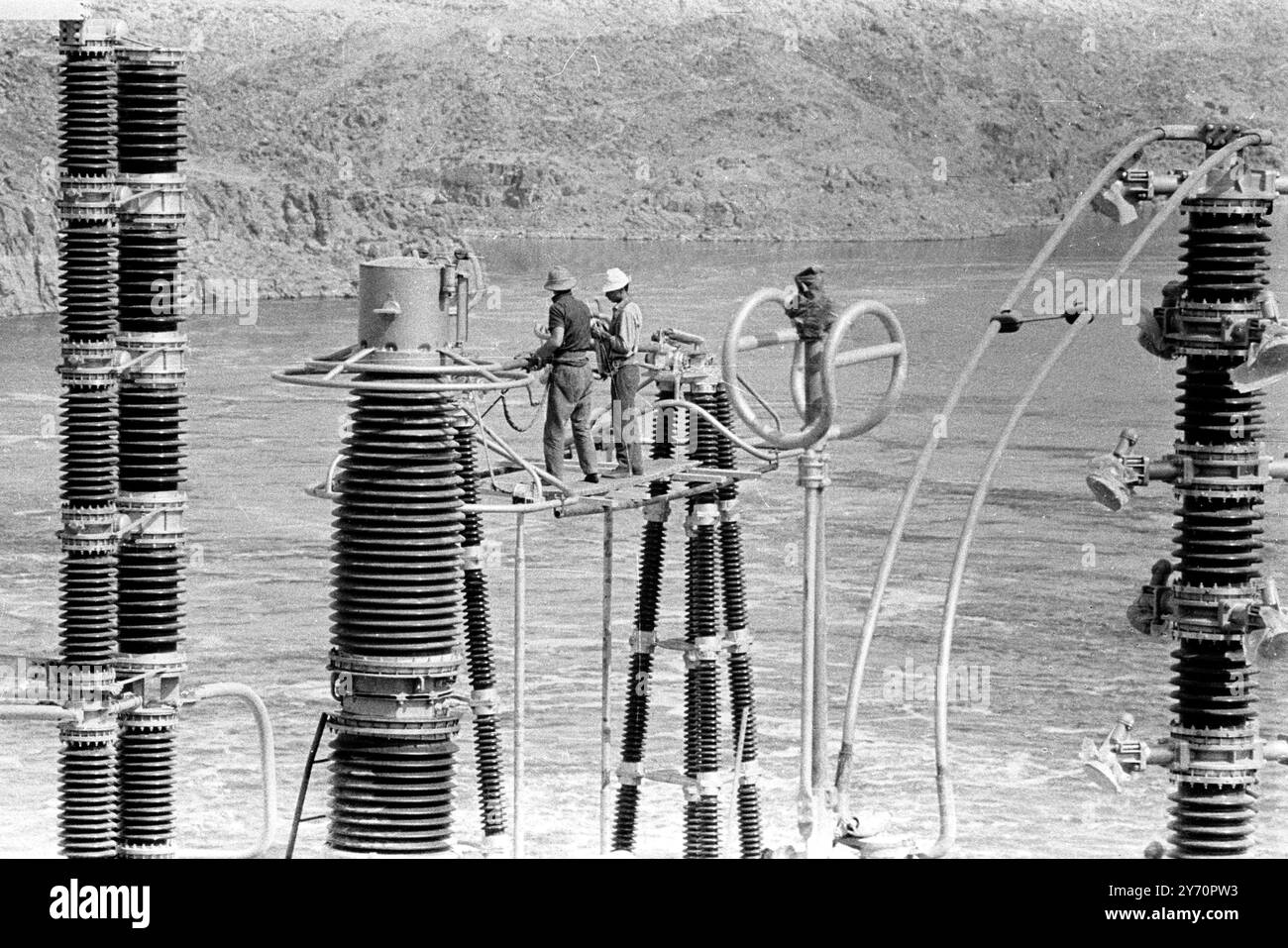 ASSUAN HIGH DAM NÄHERT SICH DER FERTIGSTELLUNG ASSUAN, ÄGYPTEN; Aus der Vogelperspektive sehen Ingenieure, die an Stromleitungen am Assuan High Dam arbeiten. 28. Januar 1968 Stockfoto