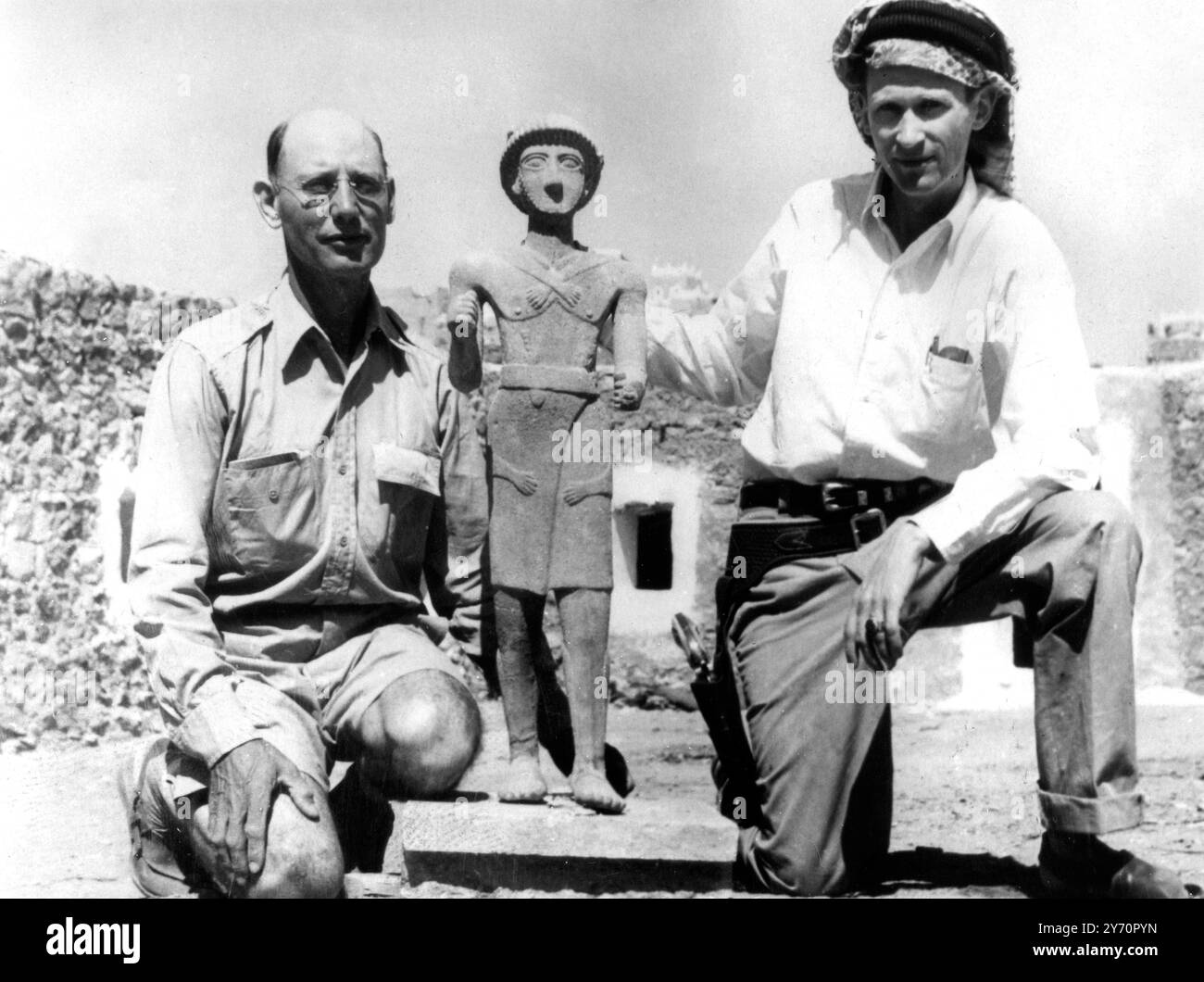 Wendell Phillips (rechts) und Professor Frank Albright mit einem der Fundstücke der Expeditionen. Auf dem Bild mit ihnen in ihrem Hauptquartier in Mareb ist eine unbezahlbare Bronzestatue aus der antiken Saba. 2500 Jahre alt stammt er aus dem Tempel des Machram Bilquis in Mareb, einem Tempel im Jemen, der ursprünglich im 8. Jahrhundert v. Chr. erbaut wurde. Es trägt eine Inschrift, die besagt, dass der Mann, der die Statue geweiht hat, Ma'adkarib genannt wurde. Von enormer Bedeutung ist das Messer im Gürtel, ähnlich dem, was heute von Nachfahren getragen wird. Die Statue wurde von der American Foundation for the Study of man entdeckt. Es wurde entlang W aufgegeben Stockfoto