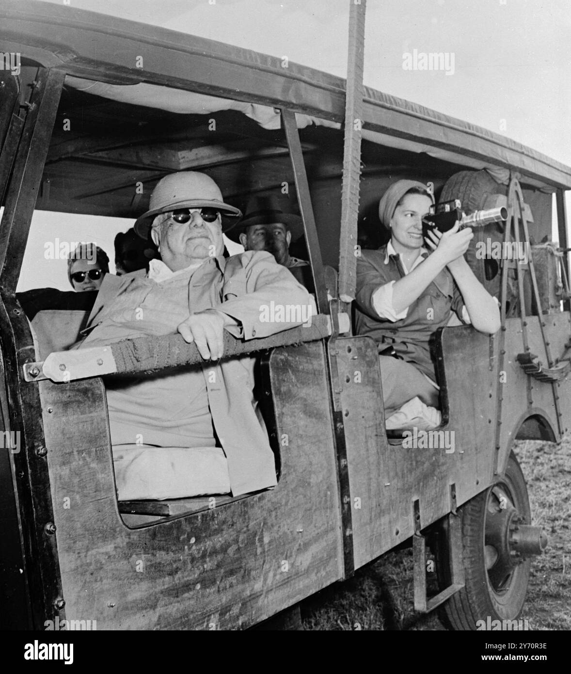 Der 73 Jahre alte Aga Khan ' Croesus ' - der Begum (rechts) wird bei der Arbeit mit einer teleskopischen Filmkamera während der Expedition gesehen, die der Aga Khan in dunkler Brille beobachtet. Sie waren auf Safari, um wilde Tiere im ostafrikanischen Dschungel zu fotografieren. Die Expedition kostete USD4000 pro Tag und das Lager war mit herrlichen und komfortablen Wohnungen ausgestattet. 1950 Stockfoto