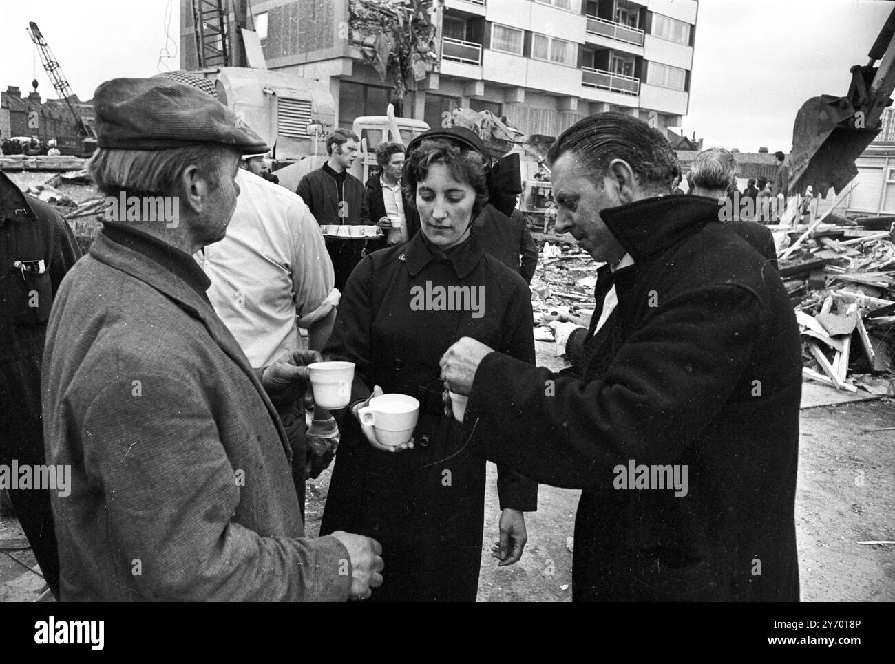 Mitglieder der Heilsarmee verteilen Begrüßungstee an die Arbeiter am Ort des heutigen teilweisen Einsturzes eines kürzlich fertiggestellten 23-stöckigen Wohnblocks im Customs House in East London . Der Zusammenbruch ereignete sich heute Morgen um 6 Uhr. Ein Augenzeuge sagte, es schien eine Explosion gegeben zu haben. Die jüngsten Zahlen sind drei Tote , neun Verletzte und sieben , darunter drei verheiratete Paare , unberücksichtigt . Die Rettungseinsätze erfolgten später wegen der gefährlichen Situation, in der die Männer arbeiteten. - Der Turm ist auch bekannt als Ronan Point, benannt nach de Stockfoto