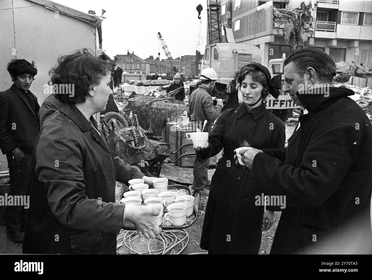 Mitglieder der Heilsarmee verteilen Begrüßungstee an die Arbeiter am Ort des heutigen teilweisen Einsturzes eines kürzlich fertiggestellten 23-stöckigen Wohnblocks im Customs House in East London . Der Zusammenbruch ereignete sich heute Morgen um 6 Uhr. Ein Augenzeuge sagte, es schien eine Explosion gegeben zu haben. Die jüngsten Zahlen sind drei Tote , neun Verletzte und sieben , darunter drei verheiratete Paare , unberücksichtigt . Die Rettungseinsätze erfolgten später wegen der gefährlichen Situation, in der die Männer arbeiteten. - Der Turm ist auch bekannt als Ronan Point, benannt nach de Stockfoto