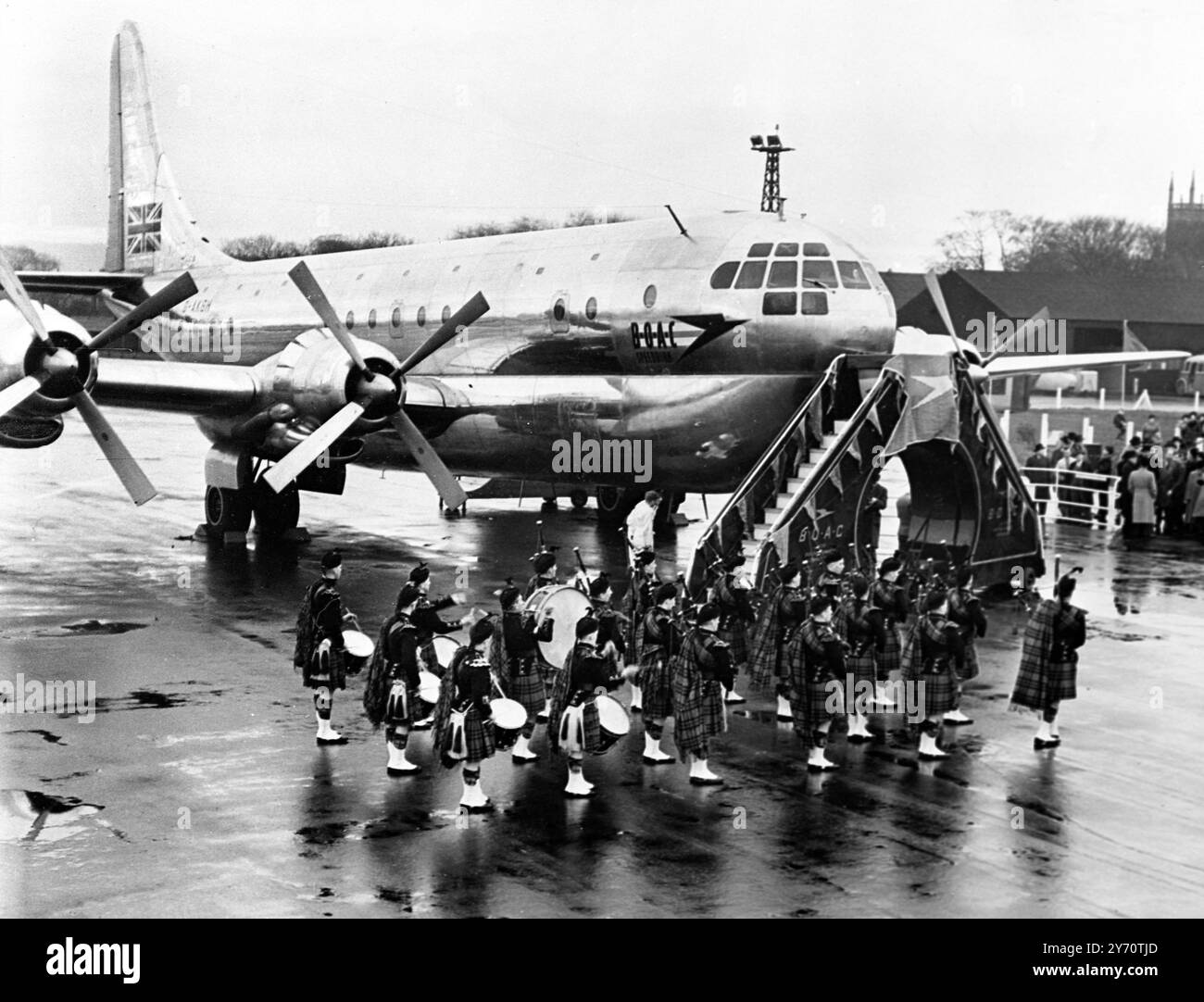 Der Flughafen Prestwick , das Zentrum eines schottischen Inlandsstreits , ist Tag und Nacht ein Hort von Aktivität . Über sein Landefeld brüllen bei jedem Wetter die Flugzeuge von einem halben Dutzend internationalen Fluggesellschaften . Britisch Kanadier , Amerikaner , Niederländer , Franzosen und Skandinavier . Die Caledonia , Flaggschiff der Flotte von Stratocruisern der BOAC auf dem Vorfeld von Prestwick kurz nach ihrer Taufe durch Lord Pakenham , Minister für Zivilluftfahrt . Das Flugzeug kann 60 Passagiere mit einer Geschwindigkeit von 340 km/h transportieren , ohne Halt für 3000 bis 4600 km . Die Shotts und Dykehead Pipe Band, aktuelle Weltmeister sind hier Stockfoto